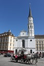 Vienna, Austria - 25 April 2012: Michaelerkirche and tourists in the horse-drawn carriage in front of it