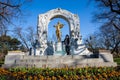 Tourist being photographed next to the Monument to Johann Strauss II at Stadtpark in a beautiful early spring day