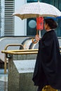 An elderly Austrian woman with a checkered umbrella and a raincoat, Vienna, Austria