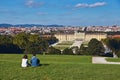 Vienna, Austria - September 24, 2014: Couple of tourists sitting on the grass with the view of Schonbrunn palace