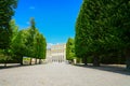 Schonbrunn Palace and tourists at end of long wide white pathway leading between trees