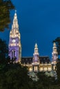 Vienna city hall with illuminated with yellow and purple lights. Towers between trees in the late evening Royalty Free Stock Photo