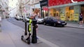 A blonde female uses a smartphone to deactivate a rental electric scooter and walks away