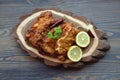 Viennese schnitzel on a wooden board with lemon on a dark background. Meat dish.