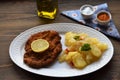 Viennese schnitzel on a wooden board with lemon on a dark background. Meat dish.