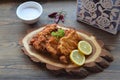 Viennese schnitzel on a wooden board with lemon on a dark background. Meat dish.