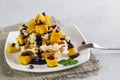 Viennese waffles with ice cream and slices of mango doused with chocolate,in a white plate on a gray background Royalty Free Stock Photo