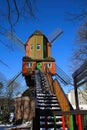 View beyond steps on red green colorfull striped wind mill Narrenmuhle against blue sky in winter