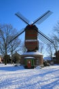 View over snow on red green colorfull striped wind mill Narrenmuhle with bare trees in winter