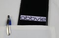 Close up of mobile phone screen with logo lettering of Abbvie pharmaceutical company in pocket of white doctors coat with pencil