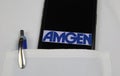 Close up of mobile phone screen with logo lettering of Amgen pharmaceutical company in pocket of white doctors coat with pencil