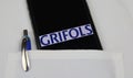 Close up of mobile phone screen with logo lettering of Grifols pharmaceutical company in pocket of white doctors coat with pencil