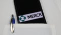 Close up of mobile phone screen with logo lettering of Merck pharmaceutical company in pocket of white doctors coat with pencil
