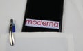 Close up of mobile phone screen with logo lettering of Moderna pharmaceutical company in pocket of white doctors coat with pencil