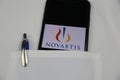 Close up of mobile phone screen with logo lettering of Novartis pharmaceutical company in pocket of white doctors coat focus on c Royalty Free Stock Photo