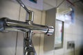 View beyond chrome faucet on blurred disinfectant dispenser and white tiled wall
