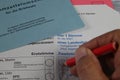 Closeup of german ballot paper for postal voting with envelopes and hand holding red pencil