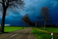 VIERSEN, GERMANY - Dark sky with hail bearing clouds over country road and bare trees announcing thunder storm.