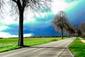 VIERSEN, GERMANY - Dark sky with hail bearing clouds over country road and bare trees announcing thunder storm. Royalty Free Stock Photo
