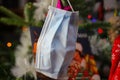 Close up of surgical face protection mask in christmas fir tree with blurred Wham last christmas song vinyl record background