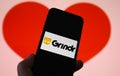 Closeup of mobile phone screen with logo lettering of online dating agency app grindr, blurred heart background