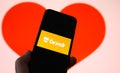 Closeup of mobile phone screen with logo lettering of online dating agency app grindr, blurred heart background