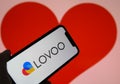 Closeup of mobile phone screen with logo lettering of online dating agency app lovoo, blurred heart background