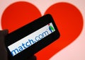 Closeup of mobile phone screen with logo lettering of online dating agency app match.com, blurred heart background