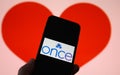 Closeup of mobile phone screen with logo lettering of online dating agency app once, blurred heart background