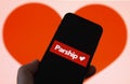 Closeup of mobile phone screen with logo lettering of online dating agency app parship, blurred heart background