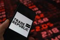 Closeup of mobile phone screen with logo lettering of trade republic brokerage, stock market chart background