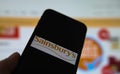 Closeup of smartphone screen with logo lettering of sainsbury supermarket , blurred website background