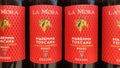 Closeup of bottles italian La Mora Maremma Toscana red wine in shelf of german store