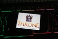 Closeup of smartphone screen with logo lettering of online game throne kingdom at war on illuminated computer keyboard