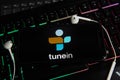 Closeup of smartphone screen with logo lettering of online internet radio service tunein on computer keyboard