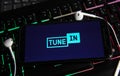 Closeup of smartphone screen with logo lettering of online internet radio service tunein on computer keyboard