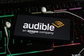 Closeup of smartphone screen with logo lettering online music streaming service amazon audible on computer keyboard