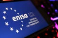 Smartphone screen with logo lettering of European Union Agency for Cybersecurity (ENISA) on computer keyboard