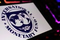 Smartphone screen with logo lettering of IMF international monetary fond on computer keyboard