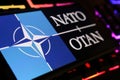 Smartphone screen with logo lettering of NATO OTAN on computer keyboard