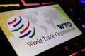 Smartphone screen with logo lettering of world trade organization WTO on computer keyboard