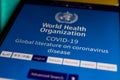 Closeup of mobile phone screen with app of world health organization about corona virus literature