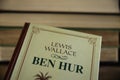 View on book cover of Lewis Wallace Ben Hur novel with stacked old books background