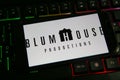 Closeup of mobile phone screen with logo lettering of film company blumhouse productions on computer keyboard