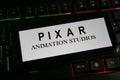 Closeup of mobile phone screen with logo lettering of film production company pixar animation studios on computer keyboard