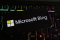 Closeup of mobile phone screen with logo lettering of microsoft bing on computer keyboard