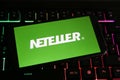 Closeup of mobile phone screen with logo lettering of neteller on computer keyboard Royalty Free Stock Photo