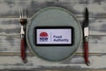 Closeup of smartphone with logo lettering of australian food safety authority nsw on plate with cutlery