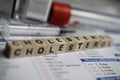 Closeup of word cholesterol on laboratory requisition slip with syringe and vial