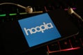 Closeup of mobile phone screen with logo lettering of streaming service hoopla on laptop keyboard Royalty Free Stock Photo